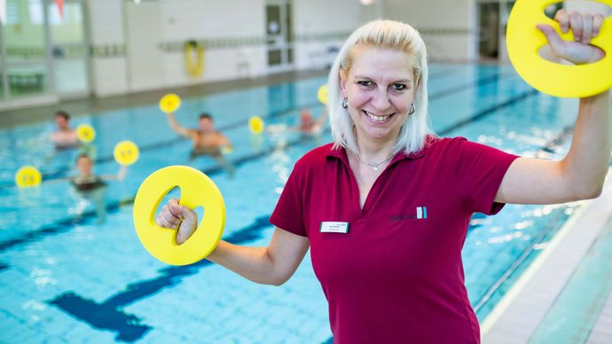 Therapeutin motiviert Patienten bei der Wassergymnastik