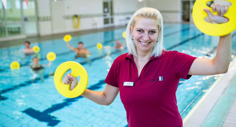 Therapeutin motiviert Patienten bei der Wassergymnastik