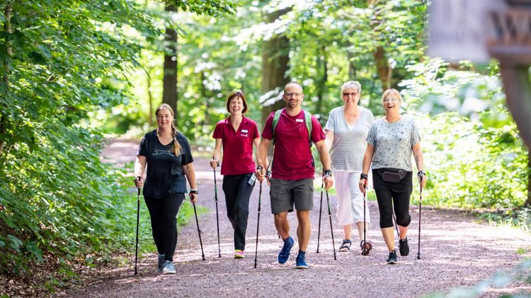 Patientegruppe wandert mit Therapeutin durch den Wald