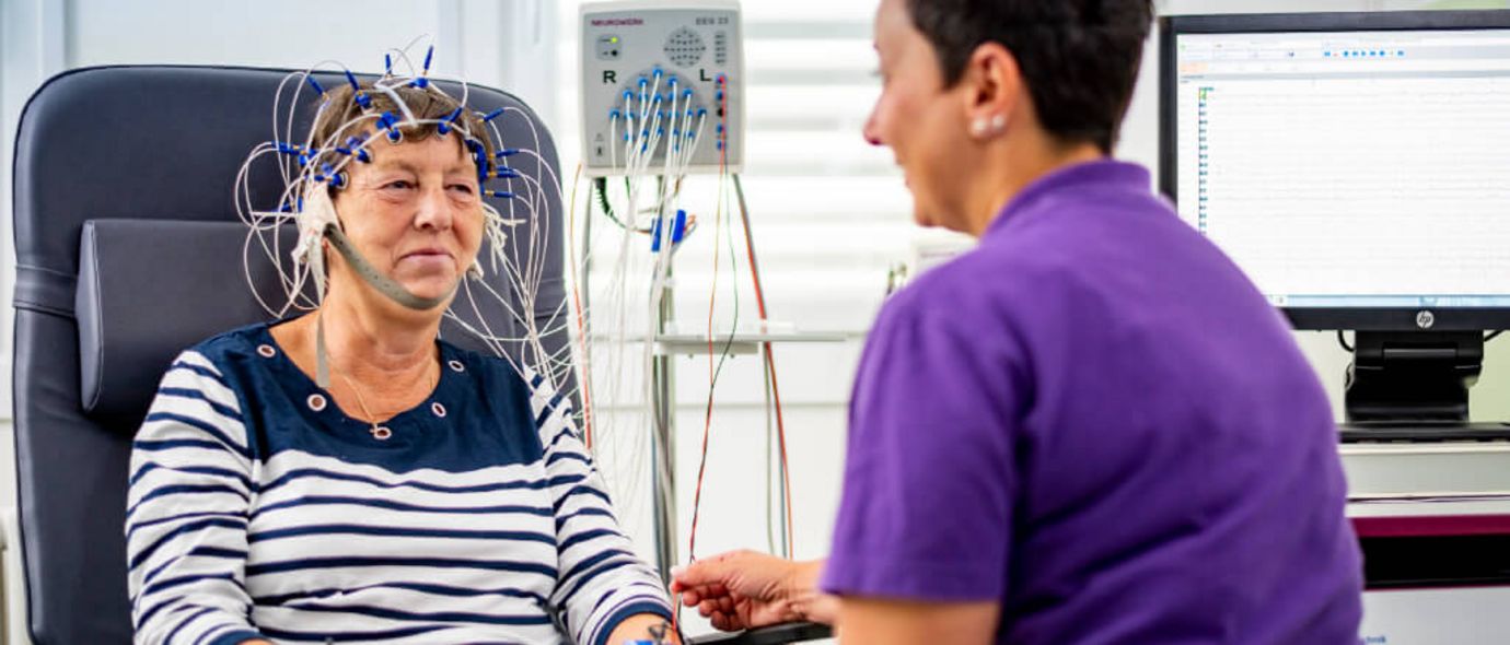 Fachkraft bereitet Patientin für Untersuchung der Gehirnströme vor