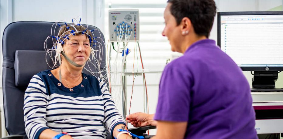 Fachkraft bereitet Patientin für Untersuchung der Gehirnströme vor