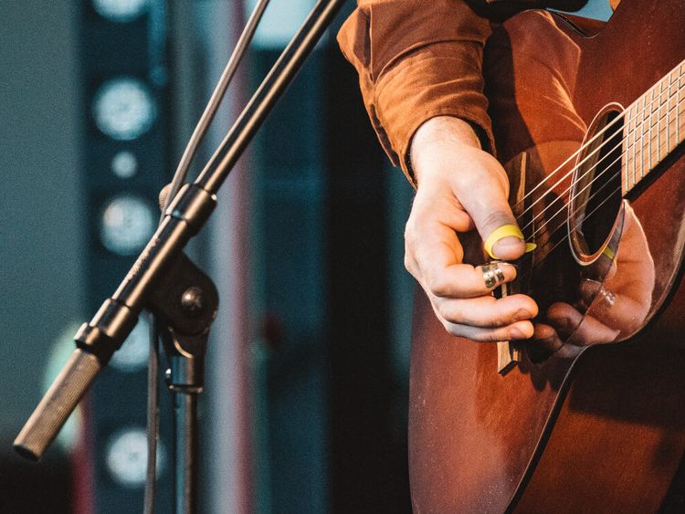 Musiker spielt Giarre auf der Bühne vor einem Mikrophone