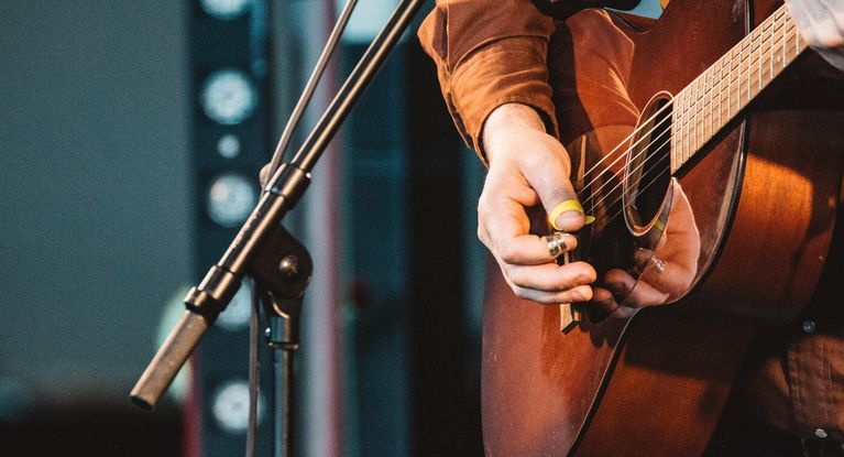 Musiker spielt Giarre auf der Bühne vor einem Mikrophone