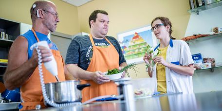 Patienten bereiten in der Lehrküche unter Anleitung einer Therapeutin gesundes Essen zu
