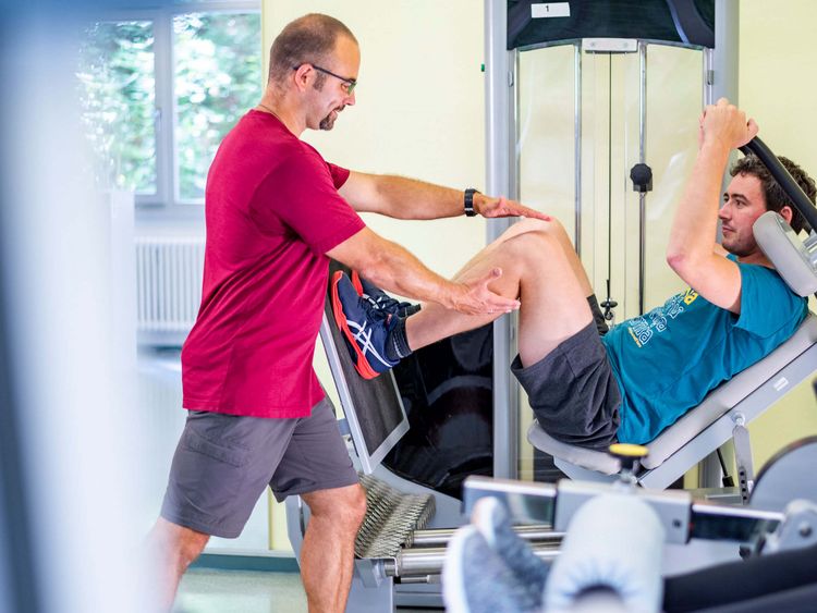 Therapeut unterstützt Patienten beim Gerätetraining im MTT-Raum