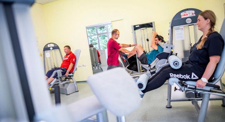Patienten und Patientinnen trainieren an Geräten im MTT-Raum