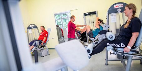 Patienten und Patientinnen trainieren an Geräten im MTT-Raum