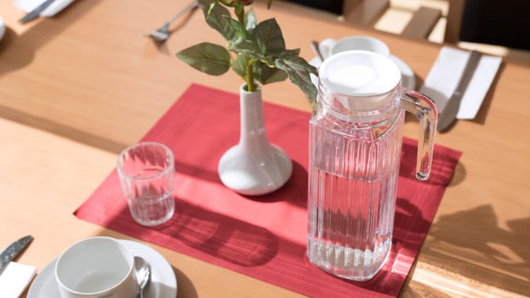 mit Tasse, Unterasse, Servietten und Kanne gedeckter Tisch